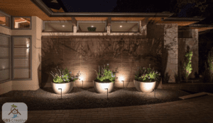 Contemporary home exterior featuring illuminated wall facade, decorative planters with garden lighting, and warm ambient lights creating a stylish outdoor setting at night.
